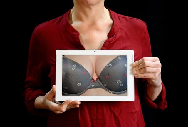 kobieta trzyma fotografię biustu w staniku push up