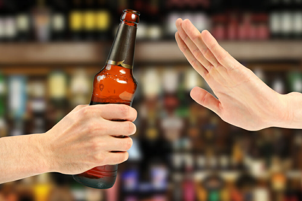 ręka zatrzymuje butelkę z alkoholem