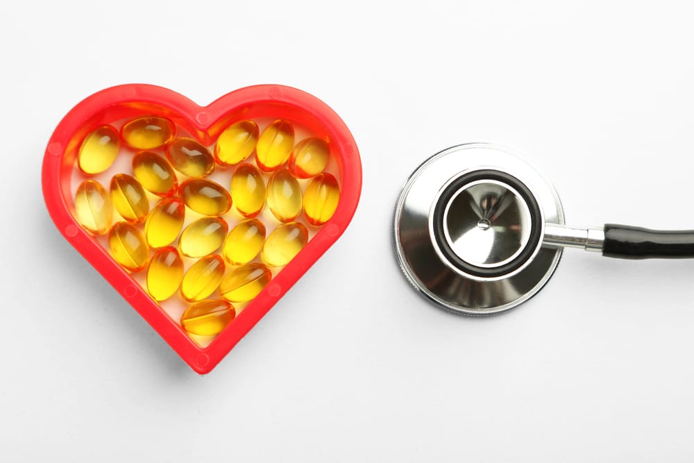 kapsułki z olejem rybim w foremce w kształcie serca, obok stetoskop